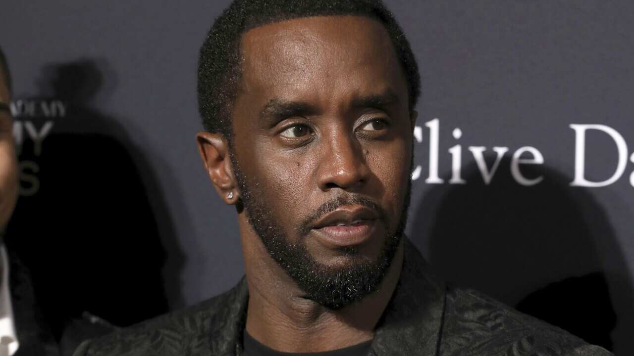 Sean Combs wearing a dark jacket, black t-shirt and silver chains on his neck