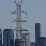 A high-voltage electricity transmission tower is seen in the foreground of the CBD skyline of Brisbane