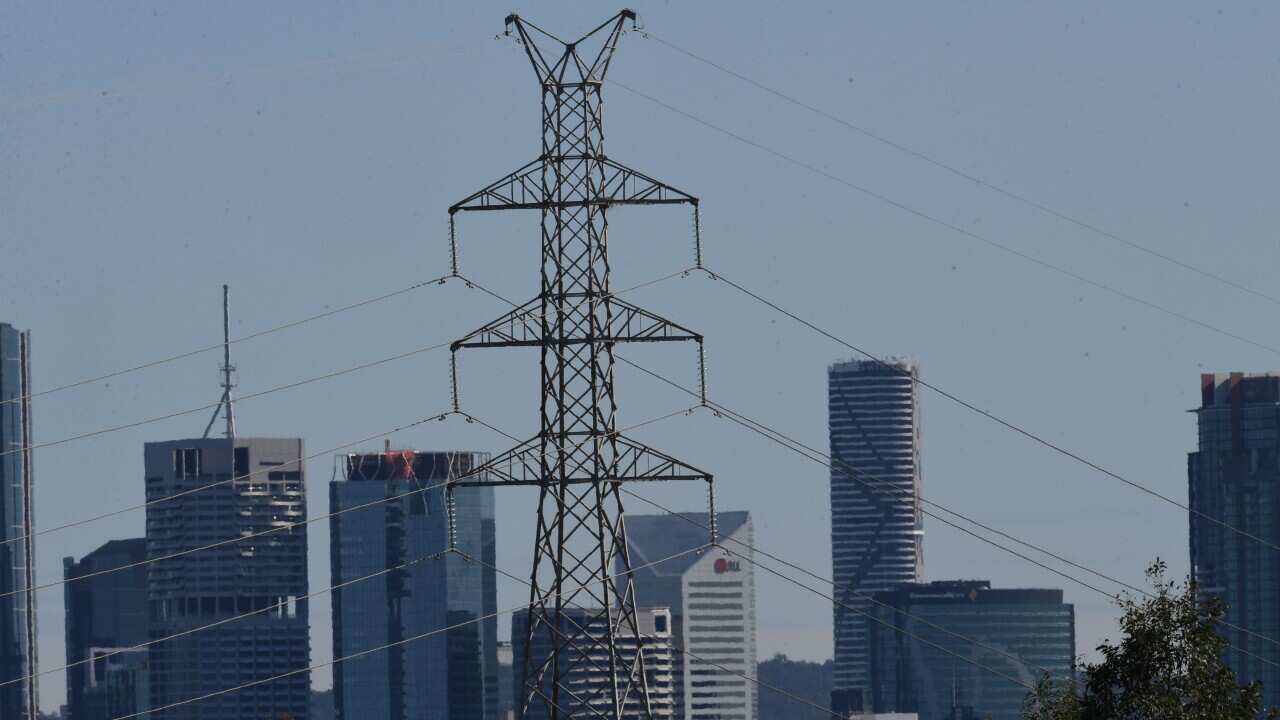 A high-voltage electricity transmission tower is seen in the foreground of the CBD skyline of Brisbane