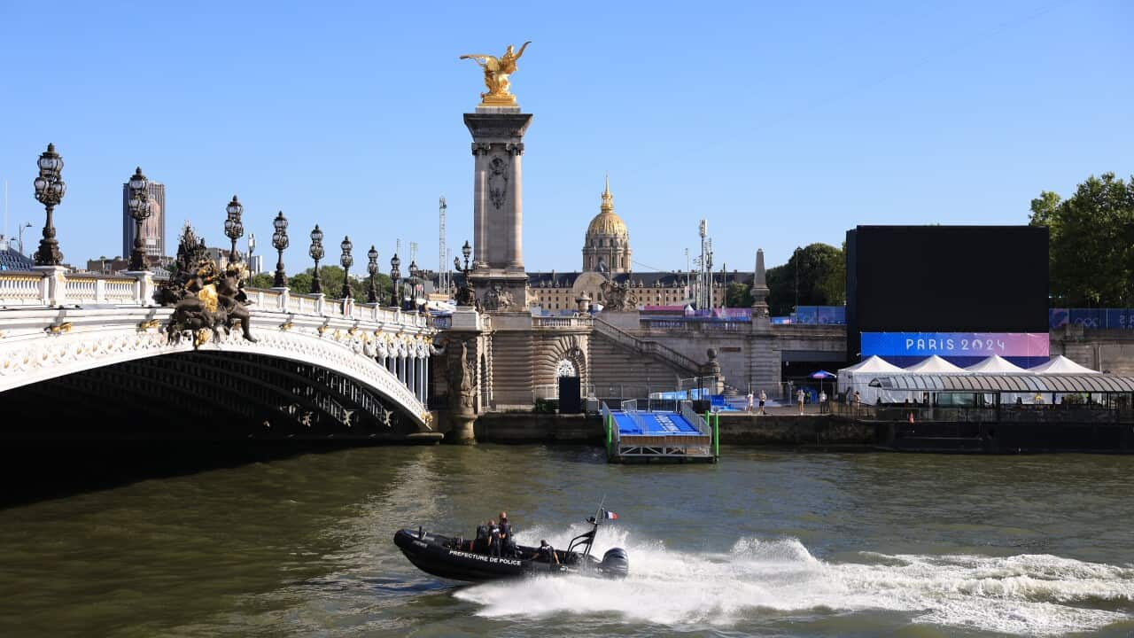 A boat speeds up a river under a bridge