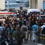 Crowds of people on the streets, with ambulances driving around them tending to the injured.