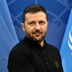 Volodymyr Zelenskyy poses for a photo with UN flags in the background.